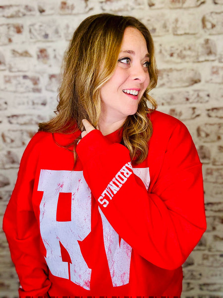Person wearing a red sweatshirt with a logo against a brick wall