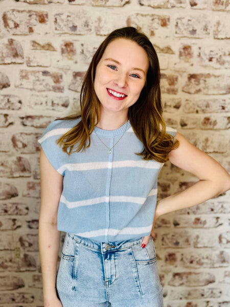 Light blue light weight sweater that is sleeveless with 4 white stripes verticslly. model is wearing with denim blue jeans