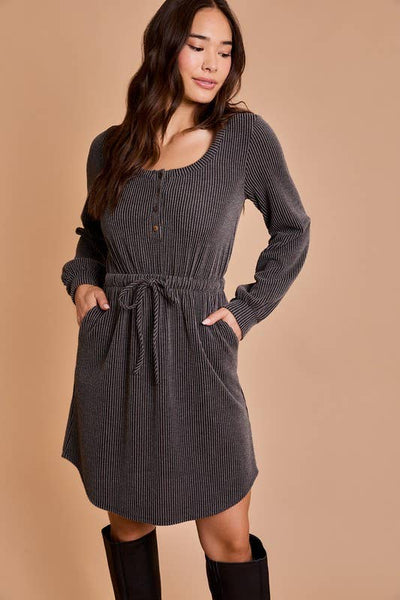 A woman wearing a gray scoop neck mini dress with long sleeves and a drawstring waist, paired with black boots.