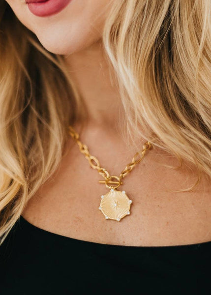 this waterproof Sunburst Diamond Chain Necklace in gold, this necklace features a thick chain, a toggle clasp, and a beautiful sunburst pendant with diamonds on it. 19.5 inches