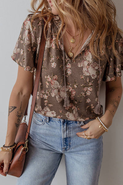 This boho split neck khaki color floral print blouse has a tie front at the neckline. model is wearing with jeans and a brown purse with accent jewelry. 
95% 