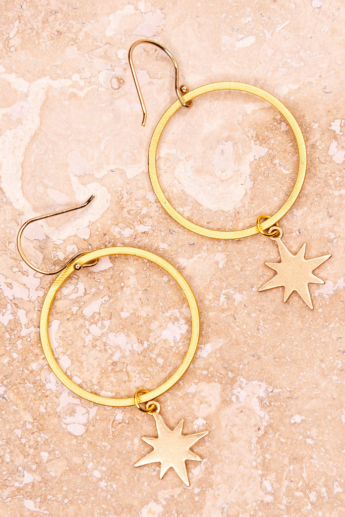 These earrings have a fishhook that connects a gold hoop with an 8-point star charm